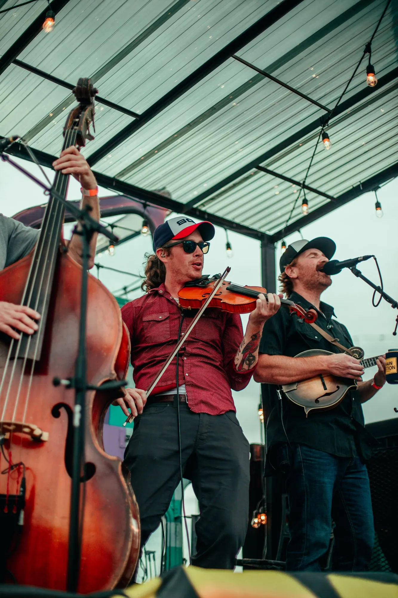 A fiddle player in a trucker cap mid-song on the Chain Station stage