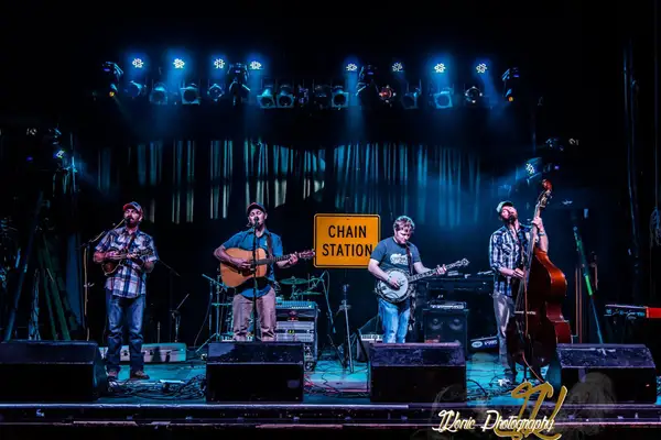 Chain Station on stage under blue light with their banner behind