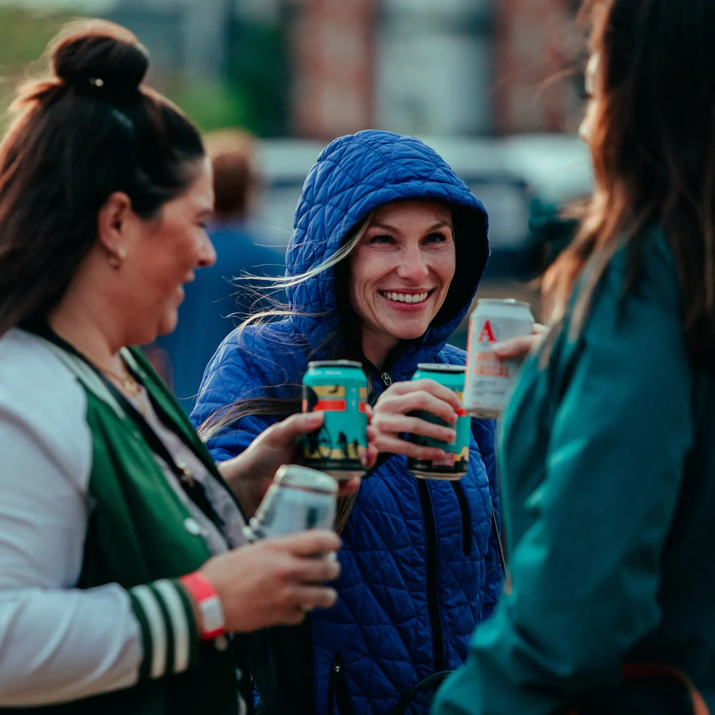 Friends clinking cans across the table at the RiNo festival