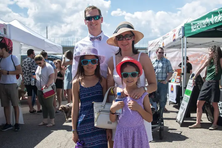 A family in derby hats and sunglasses posing in the lot.