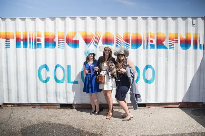 Friends in hats posing in front of the painted shipping container.