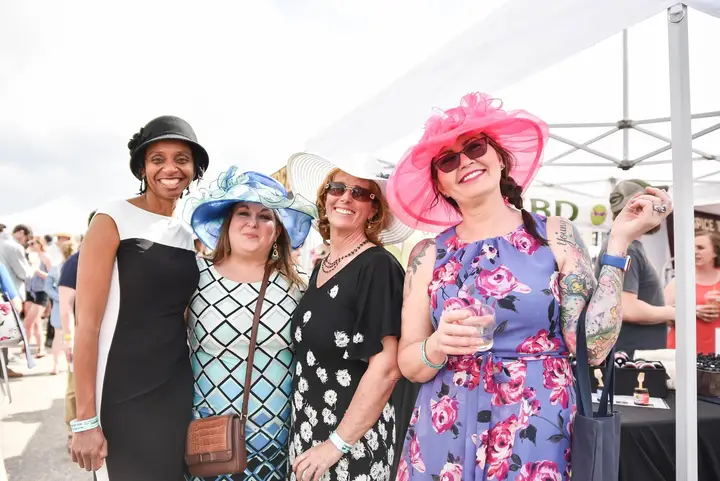 Four women in hats and spring dresses.