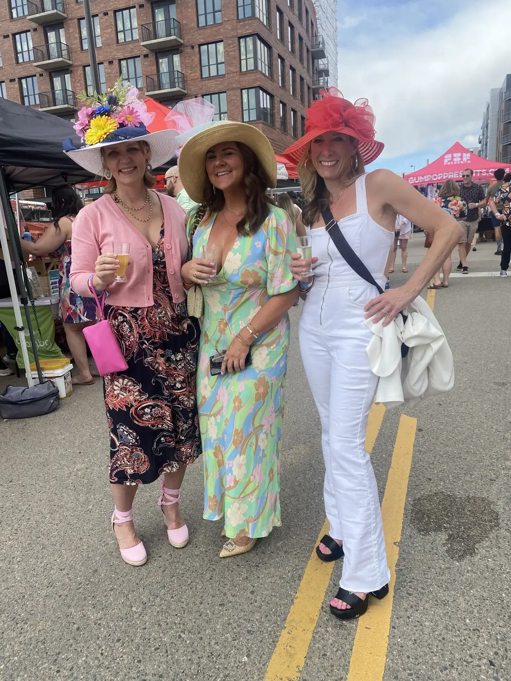 Two women in pink and fuchsia hats walking the street.