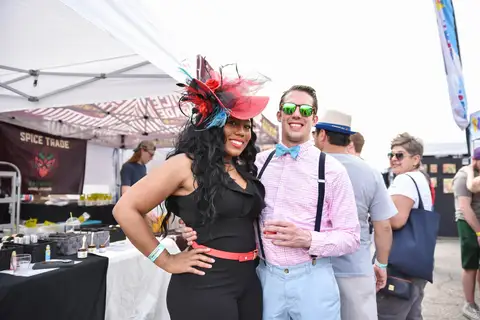 A woman in a dark fascinator with a man in suspenders.