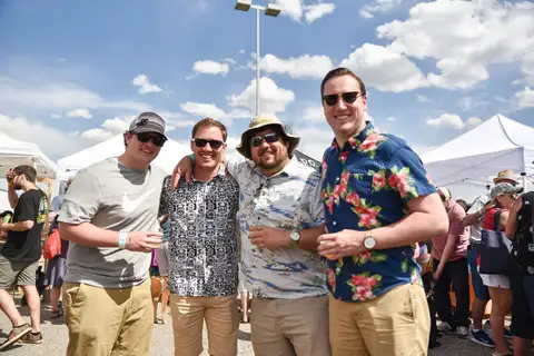 Three men in floral shirts and hats.