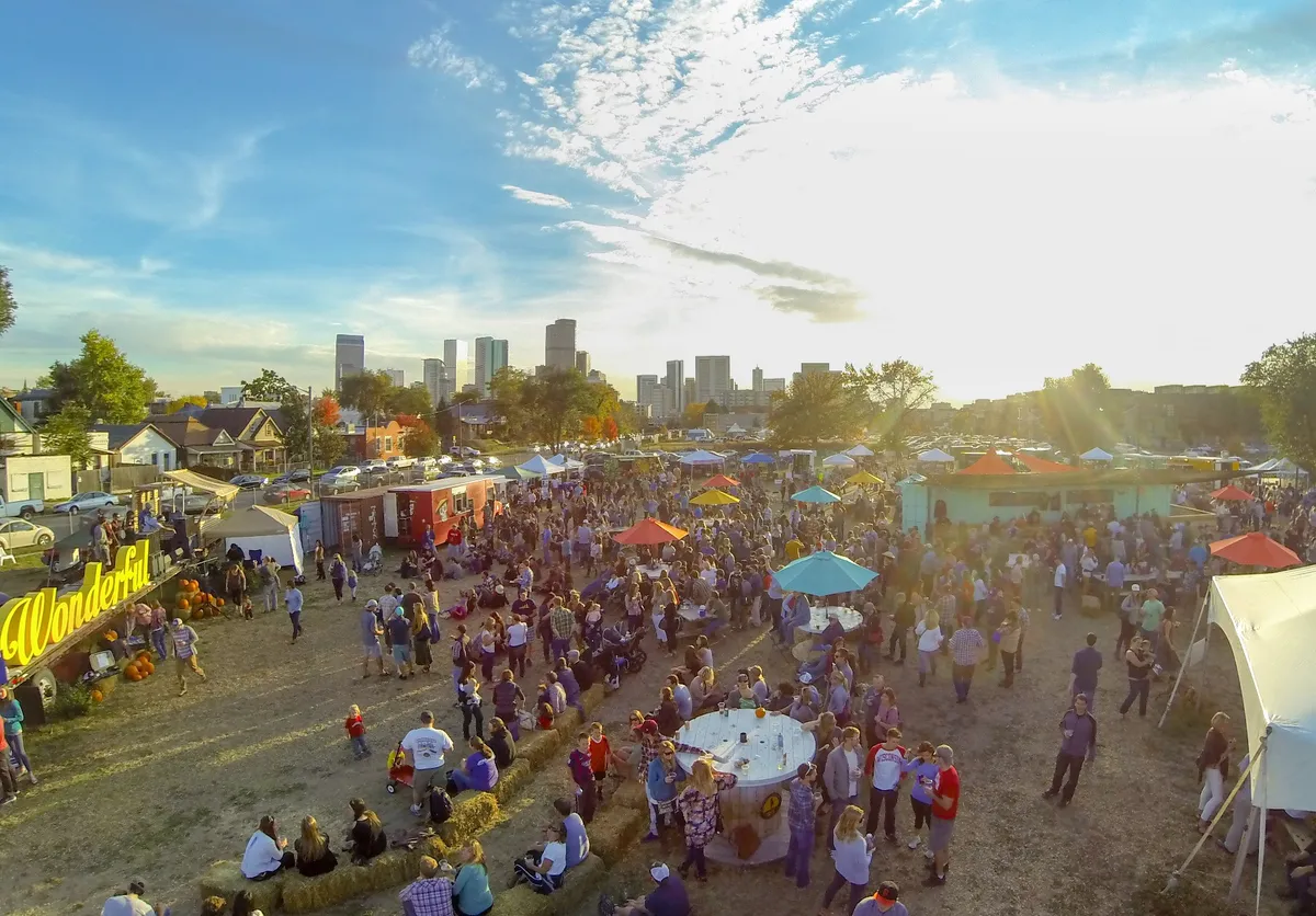 Tents and a crowd at golden hour from above, the Denver skyline on the horizon.
