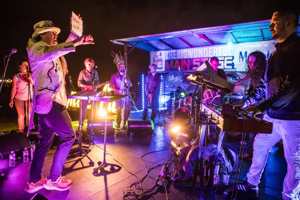 Everyone Orchestra on a stage lit magenta at Oktobergrass