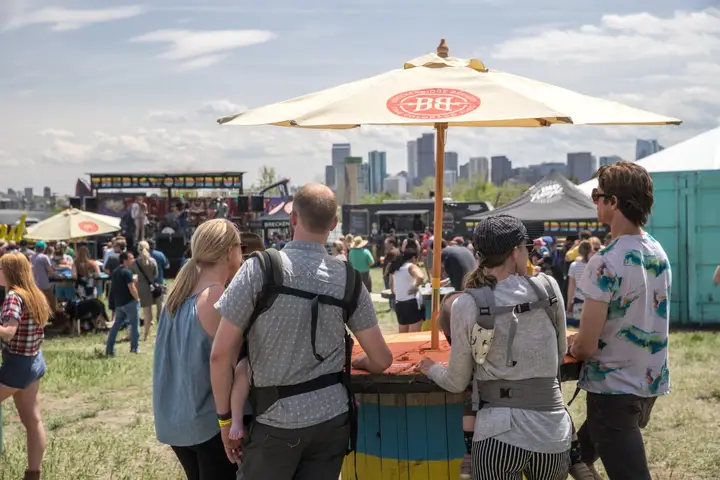 A crowd under umbrellas with the Denver skyline in the distance.
