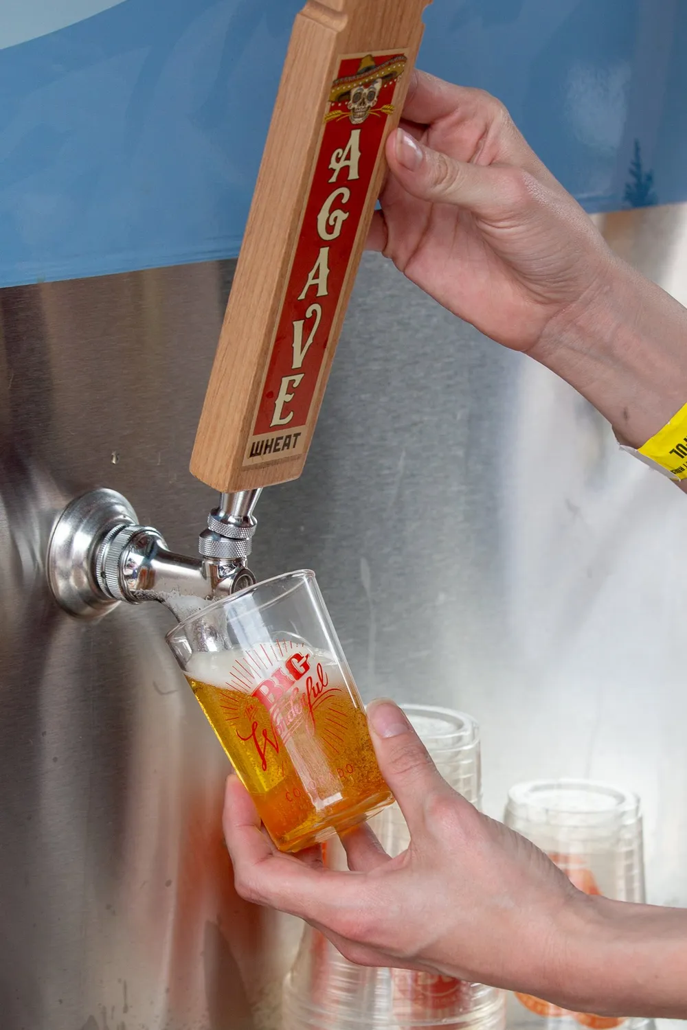 A bartender pulls a pint from a tap handle, bright beer catching the light