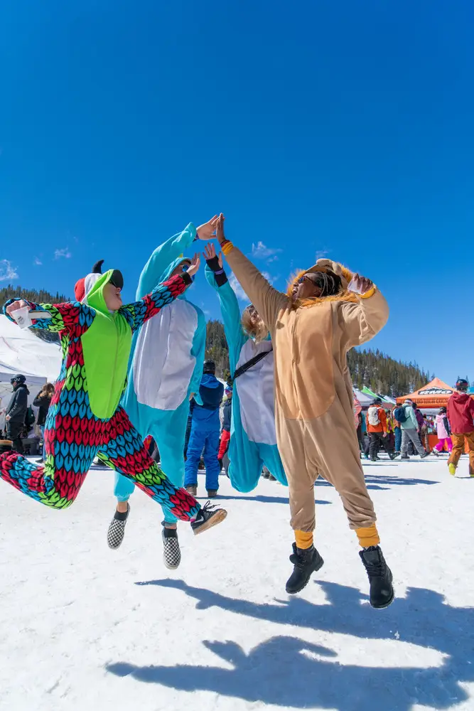 Two people in onesies jumping on the snow.