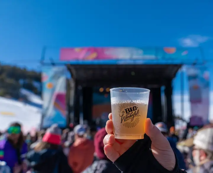 A beer held up to the stage, the Winter Park banner behind it.