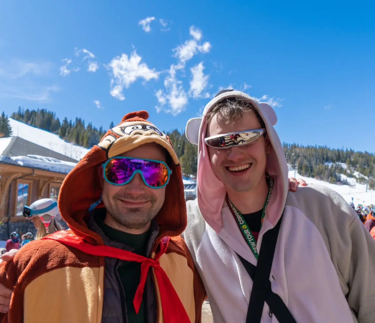 Two friends in animal onesies grinning at the camera.