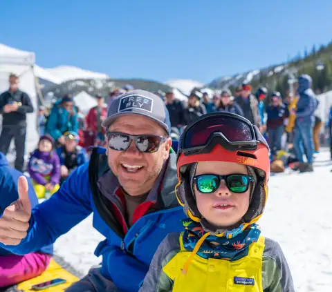 A father and son in ski gear, thumbs up.