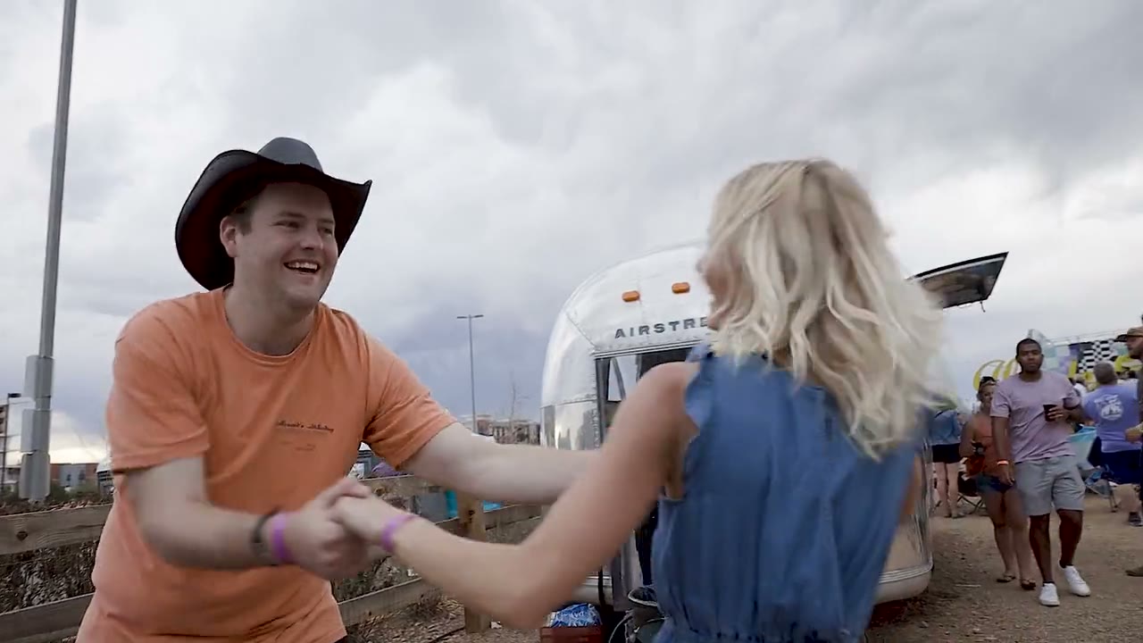A couple swing dancing in the dirt in front of a silver Airstream trailer at THEBIGWONDERFUL at Belleview Station