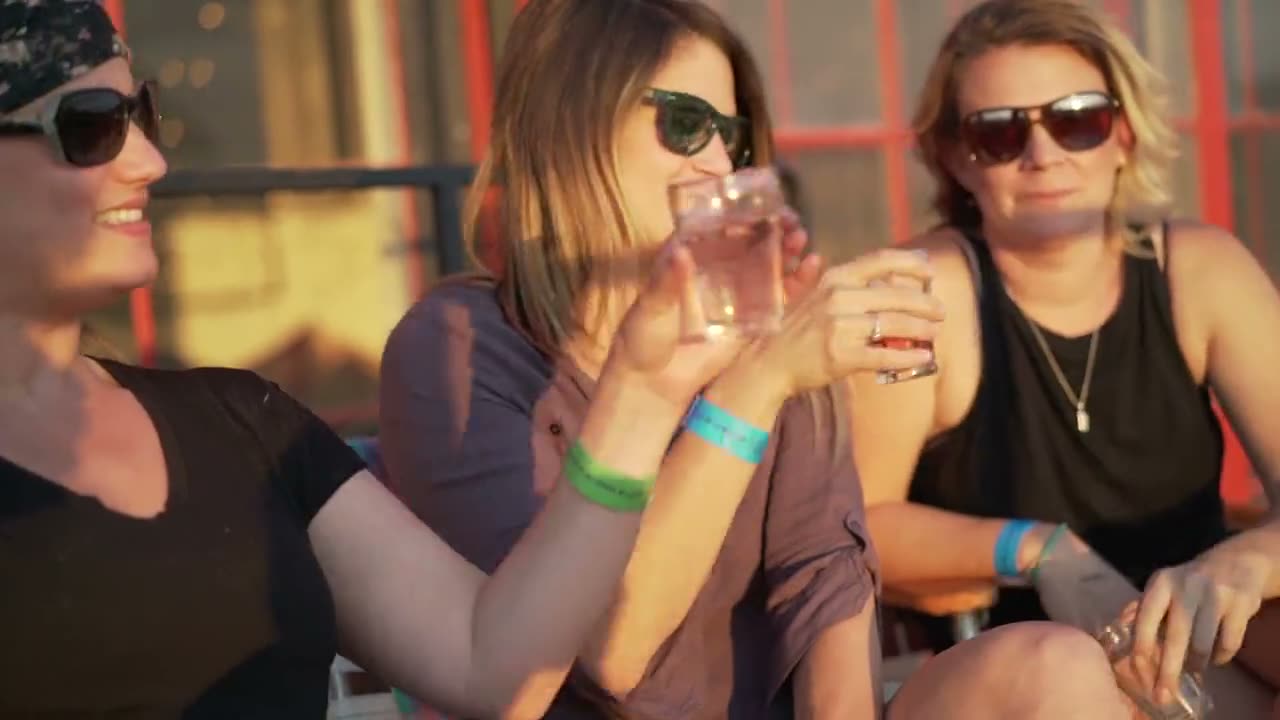 Three friends raising tasting glasses in the evening sun at THEBIGWONDERFUL at Stanley Marketplace